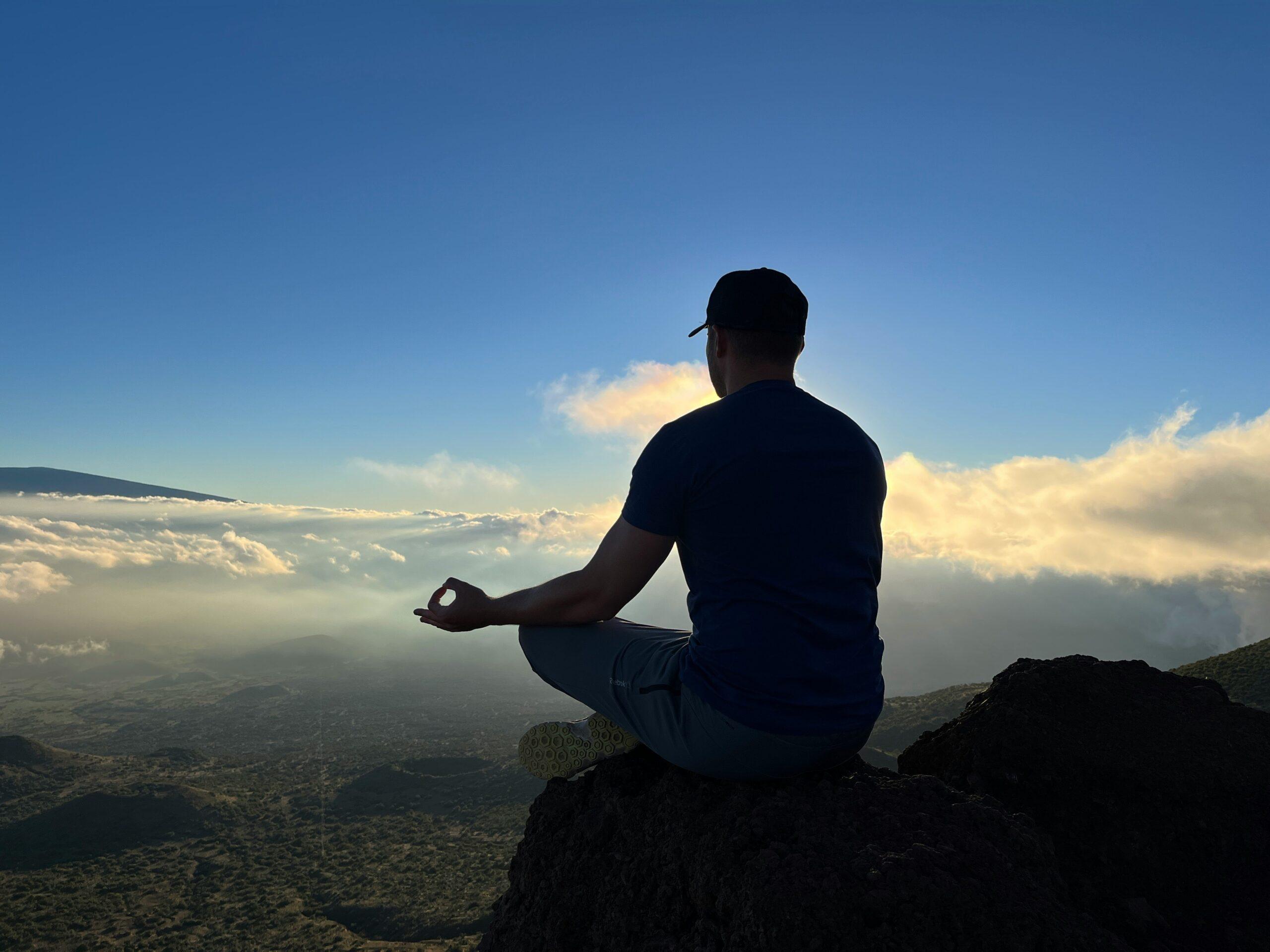 A person sitting comfortably during a brief meditation session, looking relaxed amidst clutter.