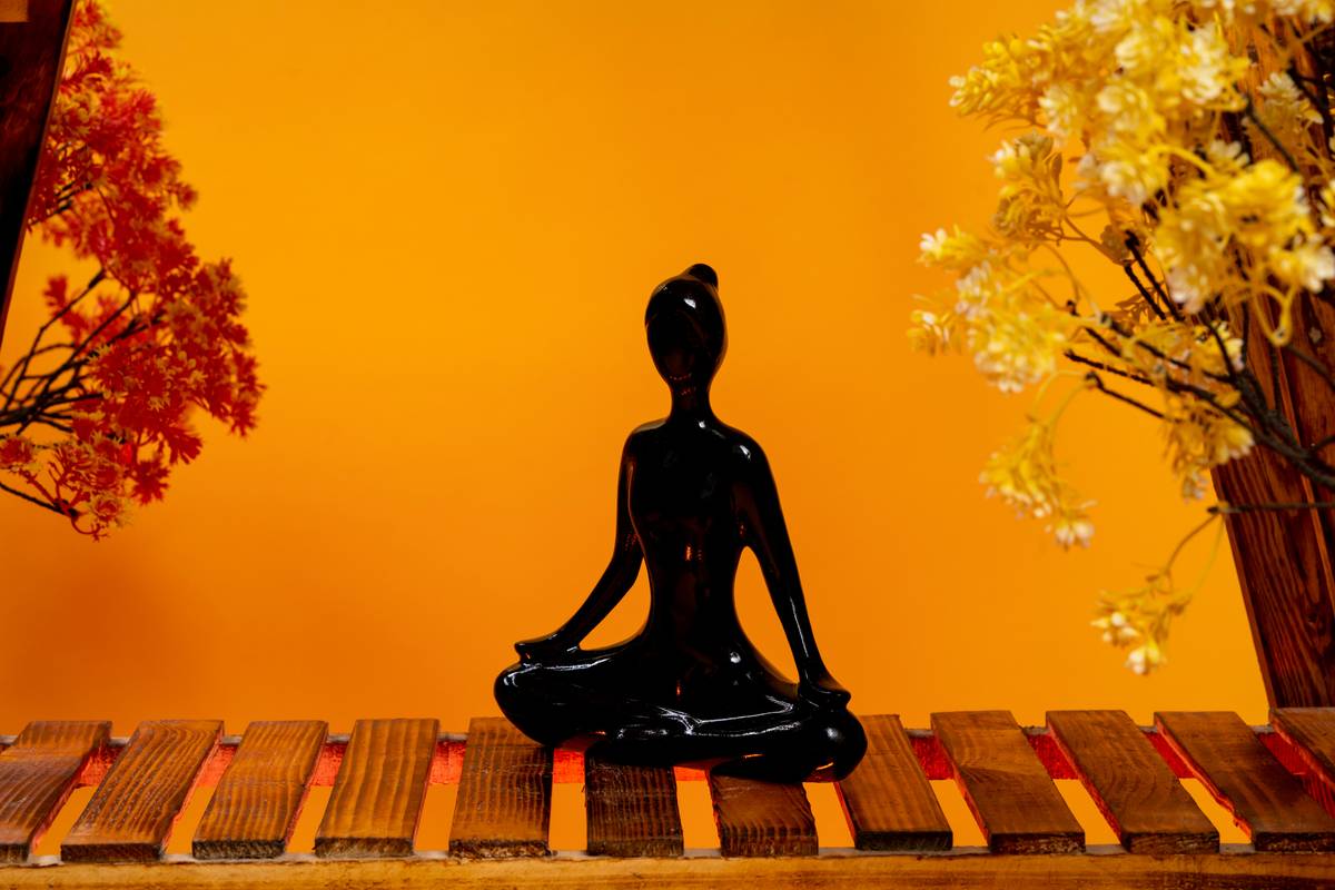 A person sitting cross-legged practicing calm guided meditation while surrounded by calming colors.