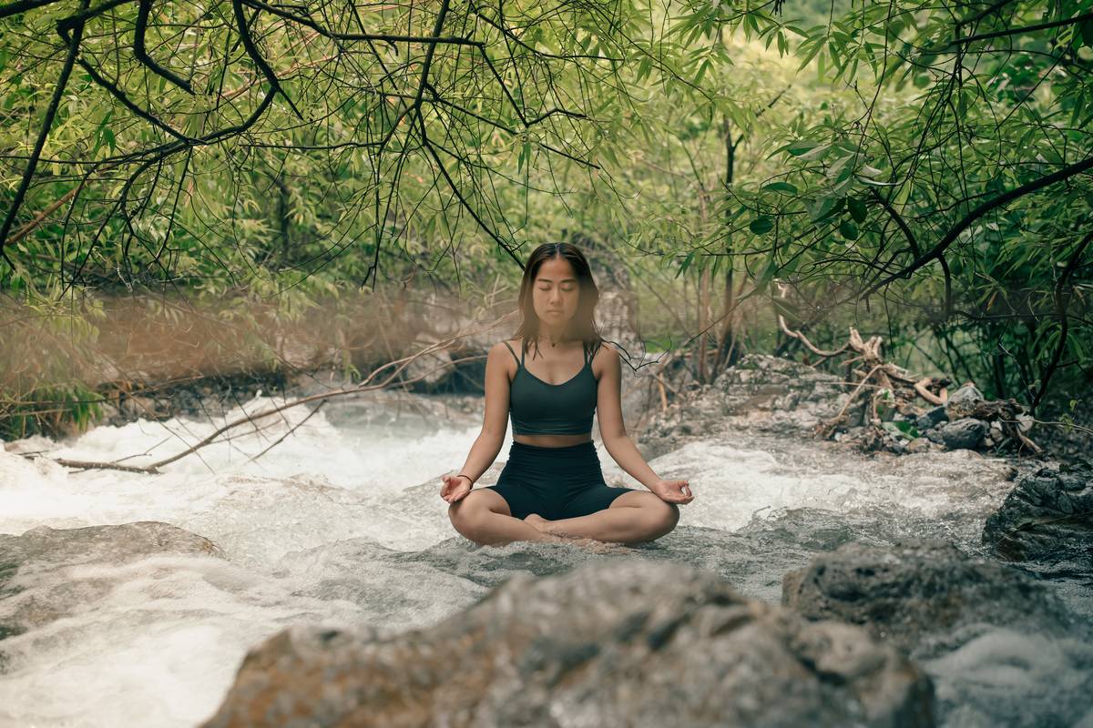 A person meditating while sitting cross-legged in a park during sunset